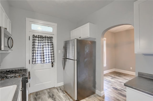 kitchen with appliances with stainless steel finishes, light hardwood / wood-style floors, and white cabinetry