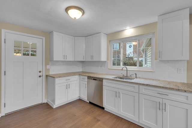 kitchen featuring backsplash, stainless steel dishwasher, sink, light hardwood / wood-style flooring, and white cabinets