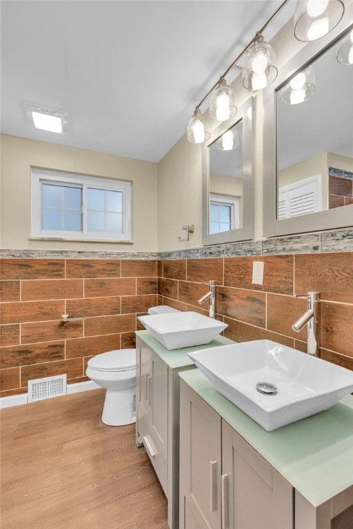 bathroom with hardwood / wood-style flooring, vanity, toilet, and tile walls