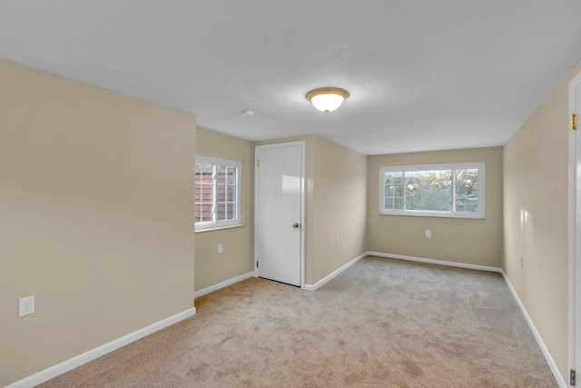 spare room featuring light colored carpet and plenty of natural light