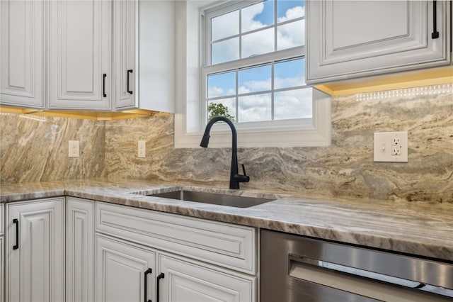 kitchen featuring backsplash, sink, white cabinets, and stainless steel dishwasher