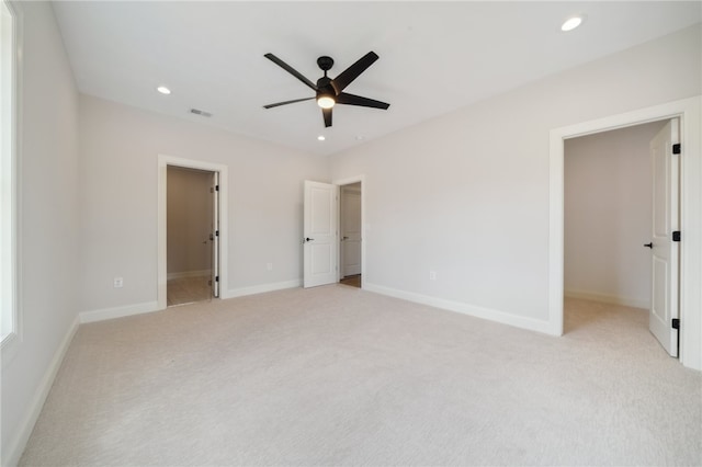 unfurnished bedroom with ceiling fan, a spacious closet, connected bathroom, light colored carpet, and a closet