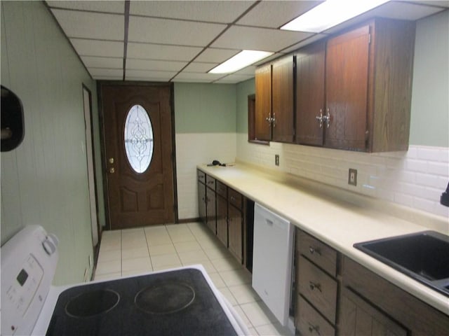 kitchen with sink, backsplash, white dishwasher, a paneled ceiling, and light tile patterned floors