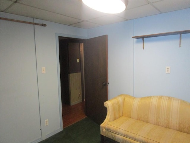 living area featuring a paneled ceiling and dark wood-type flooring