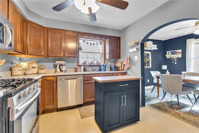 kitchen featuring a textured ceiling, stainless steel appliances, ceiling fan, and sink