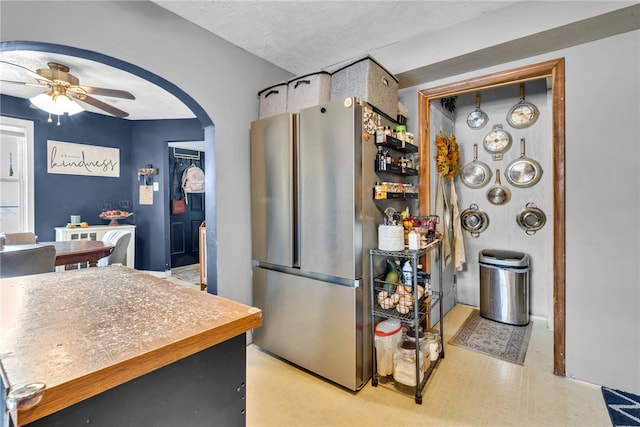 kitchen with a textured ceiling, stainless steel refrigerator, and ceiling fan