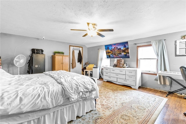 bedroom with ceiling fan, light hardwood / wood-style floors, and a textured ceiling