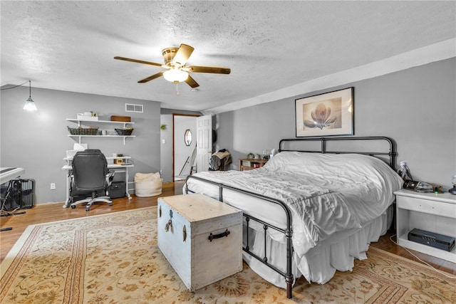 bedroom with a textured ceiling, light hardwood / wood-style flooring, and ceiling fan