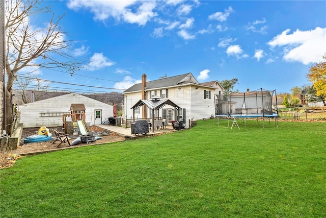 back of property featuring a lawn, a patio area, a playground, and a trampoline