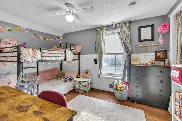 bedroom with ceiling fan, wood-type flooring, and a textured ceiling