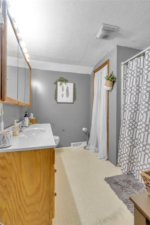 bathroom with vanity, a textured ceiling, and toilet