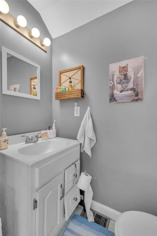 bathroom with tile patterned flooring, vanity, toilet, and lofted ceiling