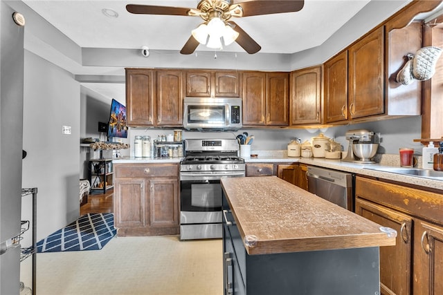 kitchen featuring a center island, light carpet, sink, ceiling fan, and stainless steel appliances