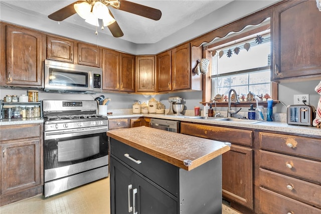 kitchen with ceiling fan, sink, a kitchen island, and stainless steel appliances