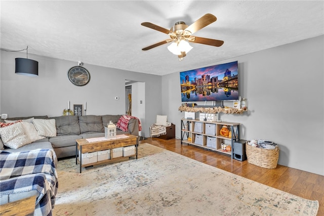 living room with a textured ceiling, hardwood / wood-style flooring, and ceiling fan