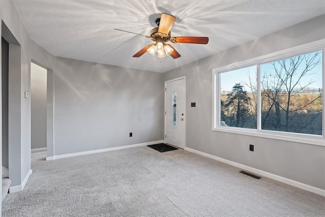 carpeted spare room with ceiling fan and a textured ceiling