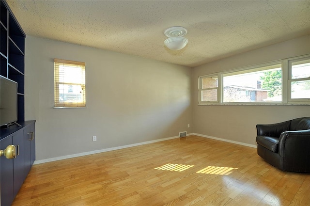 living area with a textured ceiling and light hardwood / wood-style flooring