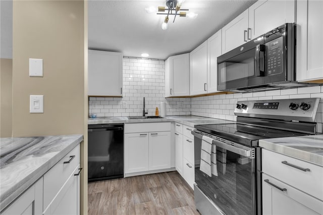 kitchen with black appliances, white cabinets, and sink