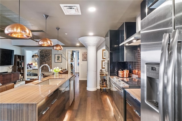 kitchen featuring dark hardwood / wood-style flooring, stainless steel appliances, sink, a center island, and hanging light fixtures