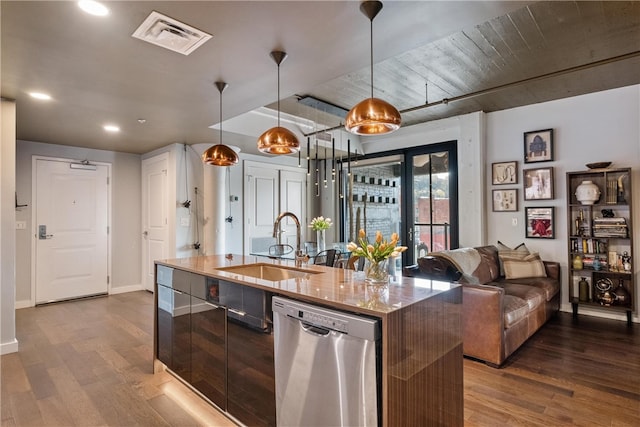 kitchen featuring dark hardwood / wood-style flooring, pendant lighting, an island with sink, and stainless steel dishwasher