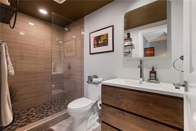 bathroom featuring a tile shower, vanity, and toilet