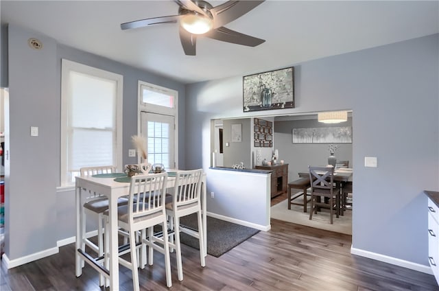 dining area with ceiling fan and dark wood-type flooring