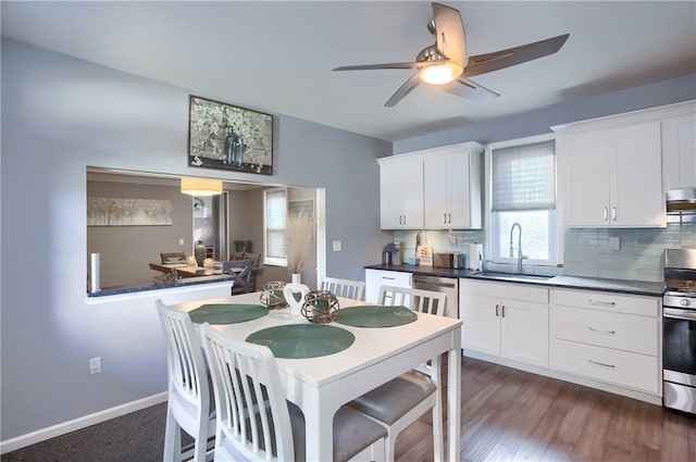 kitchen with appliances with stainless steel finishes, white cabinetry, dark wood-type flooring, and sink