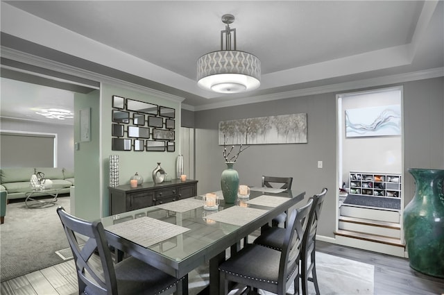 dining room featuring a raised ceiling, hardwood / wood-style floors, and ornamental molding