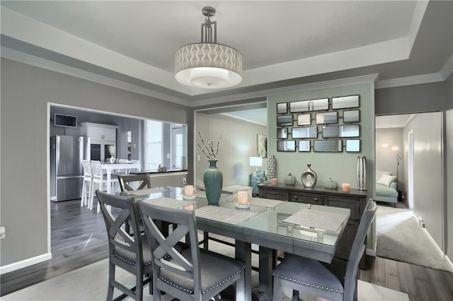 dining space featuring hardwood / wood-style floors, ornamental molding, and a tray ceiling