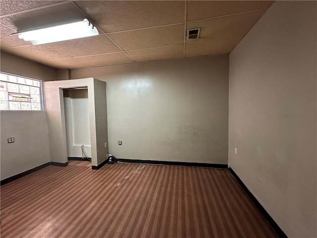 unfurnished room with dark hardwood / wood-style flooring and a paneled ceiling