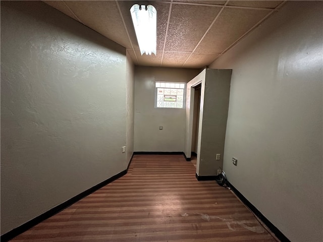 corridor with dark hardwood / wood-style floors and a drop ceiling