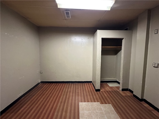 unfurnished bedroom with a paneled ceiling, dark hardwood / wood-style floors, and a closet