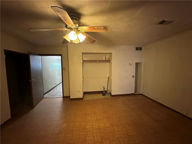 unfurnished bedroom featuring ceiling fan, a closet, and parquet floors