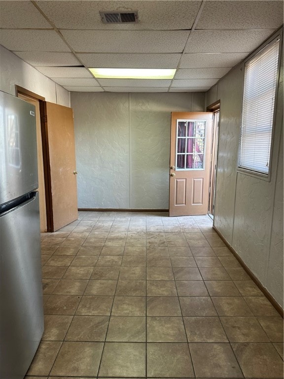 tiled spare room featuring a drop ceiling