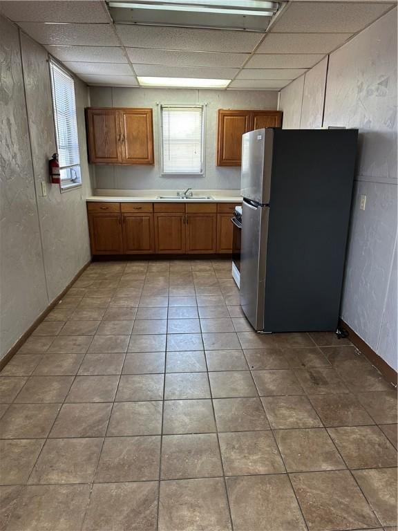 1452 Fleming Ave, Mckees Rocks, PA 15136 - kitchen featuring freestanding refrigerator, a sink, brown cabinets, a paneled ceiling, and light countertops