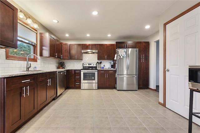 kitchen with sink, decorative backsplash, light tile patterned floors, light stone counters, and stainless steel appliances