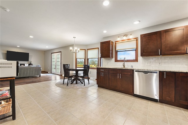 kitchen featuring dishwasher, sink, light stone counters, a chandelier, and pendant lighting