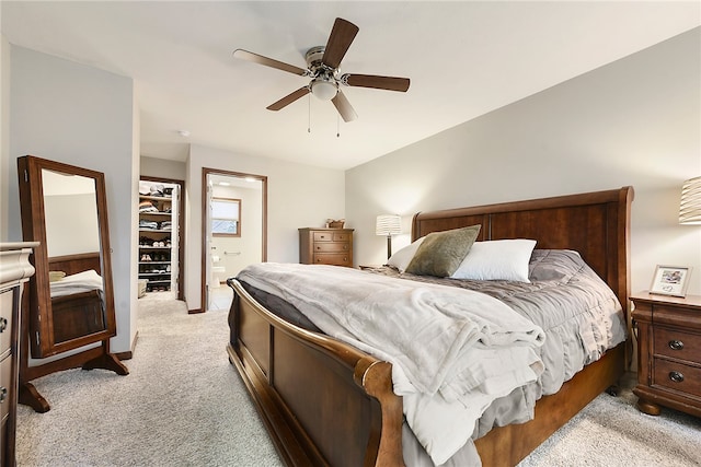 bedroom with ceiling fan, a walk in closet, light carpet, and a closet