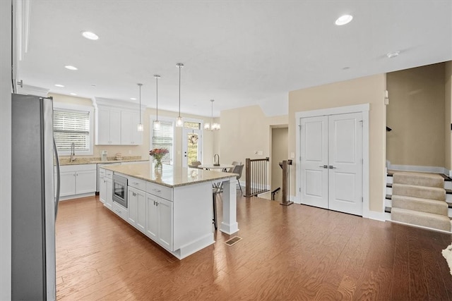 kitchen featuring white cabinets, stainless steel appliances, a kitchen island, and a wealth of natural light