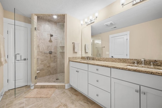 bathroom featuring a textured ceiling, vanity, and a shower with door