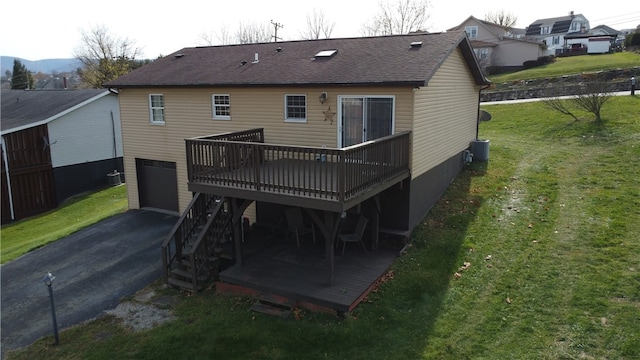 rear view of house featuring a yard, a garage, cooling unit, and a deck