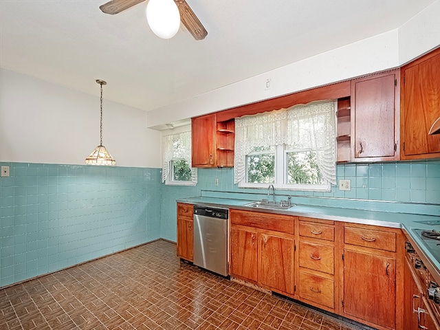 kitchen featuring ceiling fan, dishwasher, sink, hanging light fixtures, and tile walls