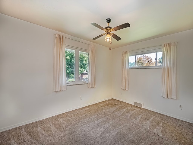 carpeted empty room featuring ceiling fan and a healthy amount of sunlight