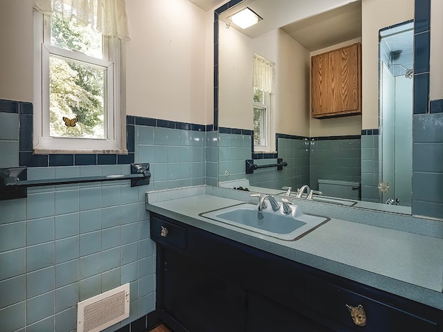 bathroom with vanity, toilet, and tile walls