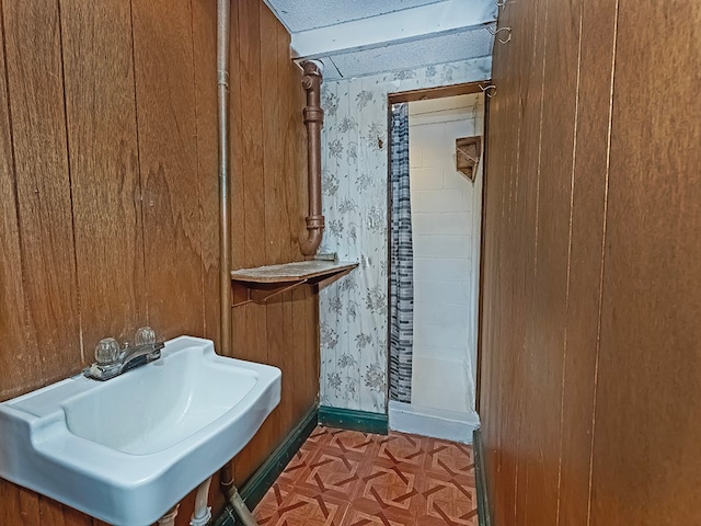 bathroom featuring sink and wooden walls