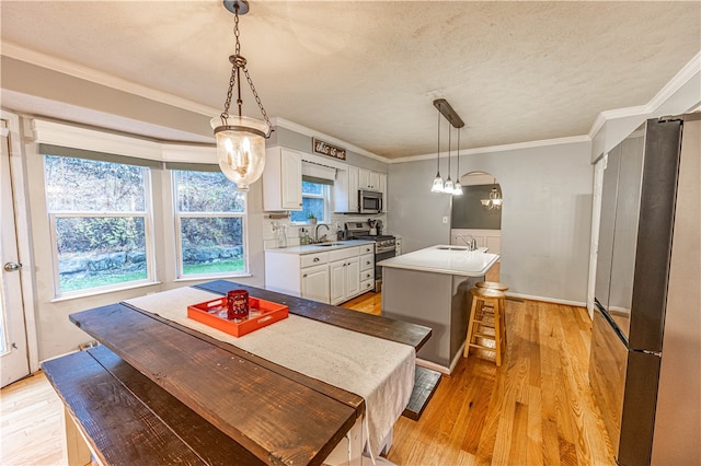 dining space with a textured ceiling, light hardwood / wood-style flooring, crown molding, and sink