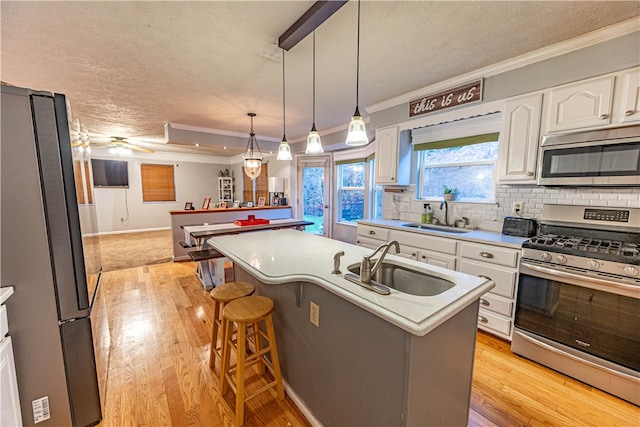 kitchen featuring sink, an island with sink, light hardwood / wood-style floors, white cabinets, and appliances with stainless steel finishes