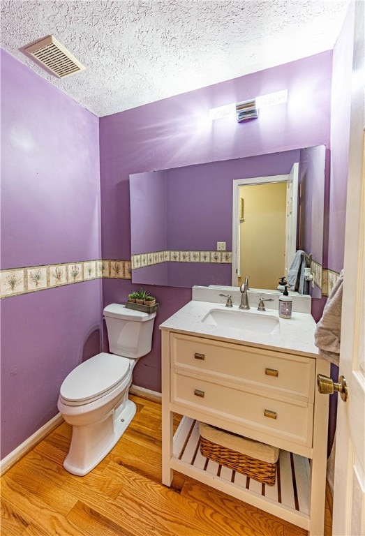 bathroom with vanity, wood-type flooring, a textured ceiling, and toilet