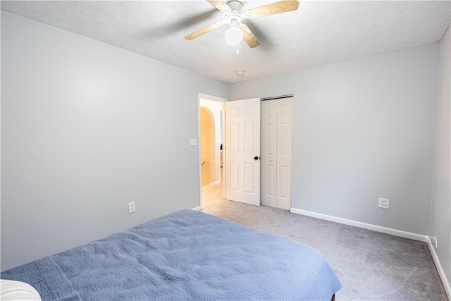 carpeted bedroom featuring ceiling fan, a closet, and a textured ceiling