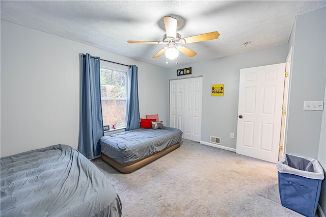 carpeted bedroom with a textured ceiling, a closet, and ceiling fan